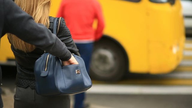 A woman on a city street does not suspect that her phone was stolen by a sly pickpocket. It crosses the road through a pedestrian crossing. The thief stole her cell phone from the bag