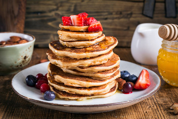Healthy oat pancakes topped with fresh strawberries and honey. Closeup view