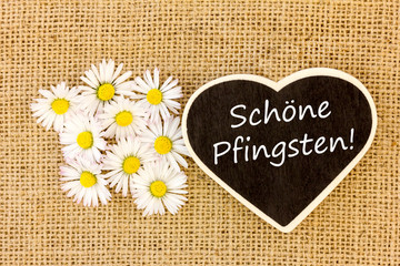 Gänseblümchen und eine Tafel mit einem Text zu Pfingsten