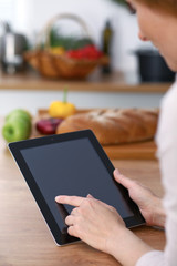 Haman hands  using touch pad in the kitchen. Closeup of woman making online shopping by tablet computer and credit card.  Cooking and shopping concept