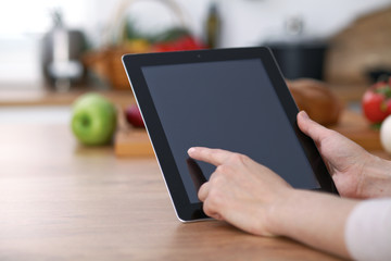 Haman hands  using touch pad in the kitchen. Closeup of woman making online shopping by tablet computer and credit card.  Cooking and shopping concept