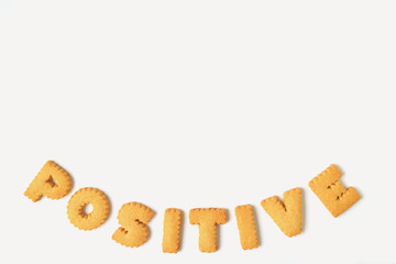 Top view of alphabet shaped biscuits, spelling the word POSITIVE, isolated on white background 