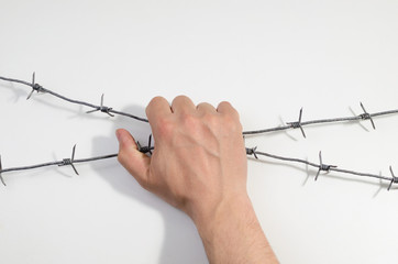 Man's hand holds onto barbed wire