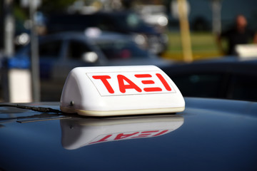 Taxi sign in Greek language on the shiny roof of a car
