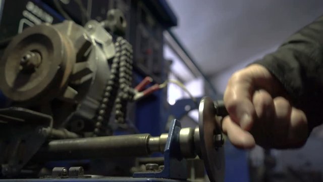 Check the car generator. The worker twists the handle of the test stand.