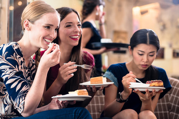 Three young women eating cake indoors