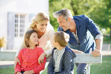 Portrait of happy family of four sitting on bench