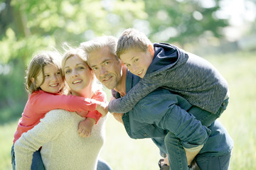 Parents giving piggyback ride to kids in countryside
