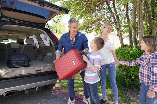 Happy Family Loading Luggage In Vehicle