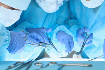 Close up of medical team performing operation. Group of surgeons at work in operating theater.