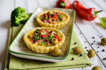 Salty tartlets with bacon, bell pepper, broccoli, cheese, onion, egg and olives