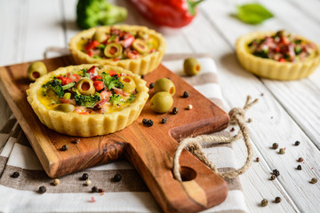 Salty tartlets with bacon, bell pepper, broccoli, cheese, onion, egg and olives