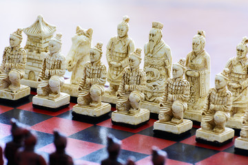 Carved chess pieces in chinese style on a chessboard.