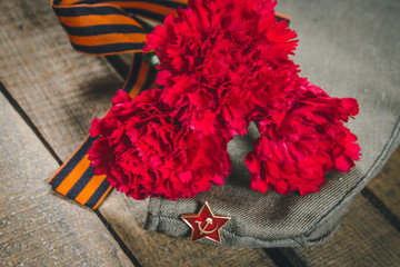 Carnation flowers, George Ribbon and military garrison cap with a red star. May 9 Victory Day
