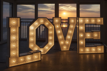 LOVE in one metre high letters lit with light bulbs at sunset at Fifteen restaurant Watergate Bay Cornwall