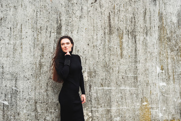 Outdoor portrait of young 35 year old woman with long dark hair, wearing black turtle neck dress