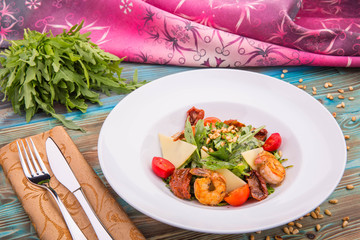 Arugula leaves with the fried tiger shrimps dried by tomatoes, pine nuts, cream Balzamik and cheese parmesan