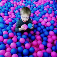 Fototapeta na wymiar a child plays in the pool with colorful balls for kids