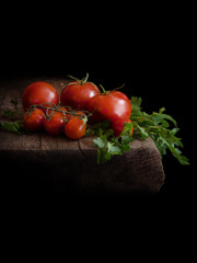 Fresh tomatoes and parsley on aged wood. Black background