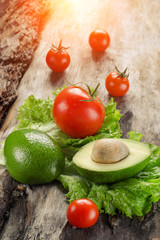 Avocado, tomatoes and salad on wooden board