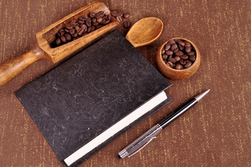 Book for recipes for making coffee. Roasted coffee beans in a wooden bowl