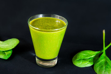 Glass of healthy green smoothie with spinach leafs on the dark background isolated. Selective focus