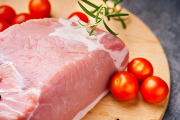 Raw pork on cutting board and tomatoes