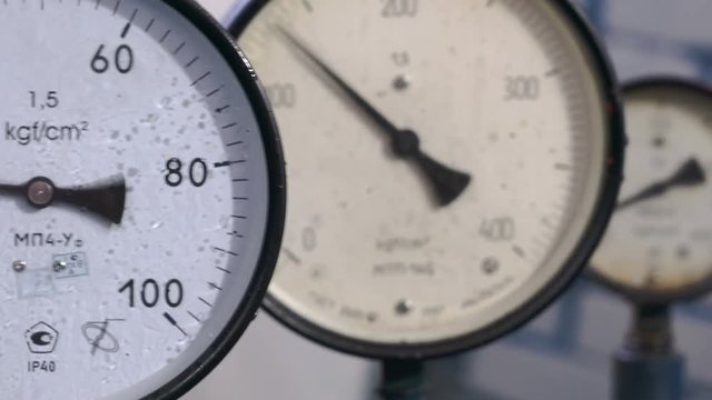 Three pressure gauges at the test bench of hydraulic equipment. Manometer arrows move. Defocusing. Close-up.