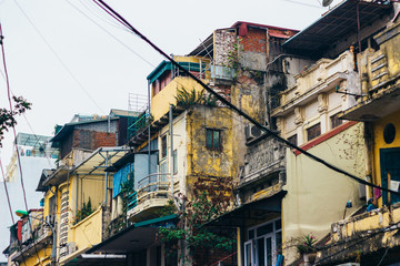Fototapeta na wymiar Details of the architecture in the Old Quarter in Hanoi. The chaos of electric wires and advertisement. Beauty in colorful details.