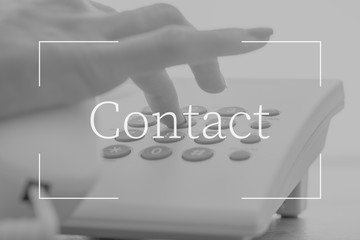 Contact text over female hand dialing a telephone number