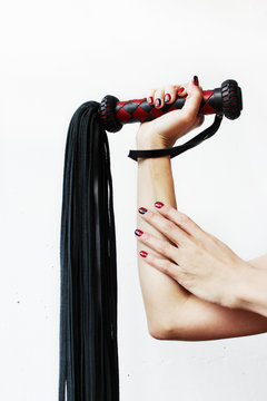 The handle of a red and black lash in a female hand on a white background.