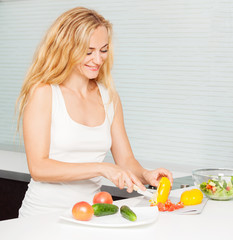 Obraz na płótnie Canvas Young woman preparing vegetable salad