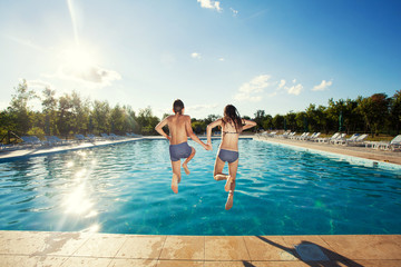 Couple jumping into pool - Powered by Adobe