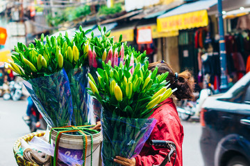 Hanoi, Vietnam - December 31, 2016: The street vendors in Hanoi, Vietnam. Woman selling flowers in the early morning on a busy street.