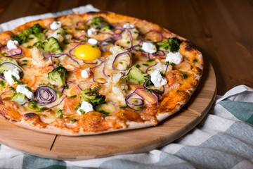 Delicious fresh homemade pizza with onions, vegetables and cheese on a wooden table. Copy space. close-up