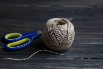 Close-up view of scissors and twine on wooden background
