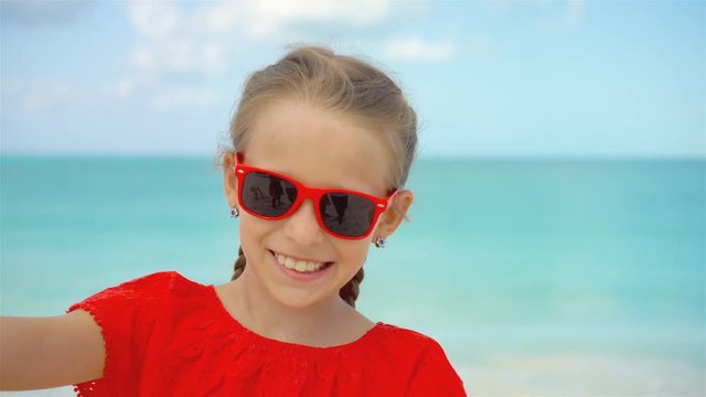 Happy little girl taking selfie at tropical beach on exotic island during summer vacation