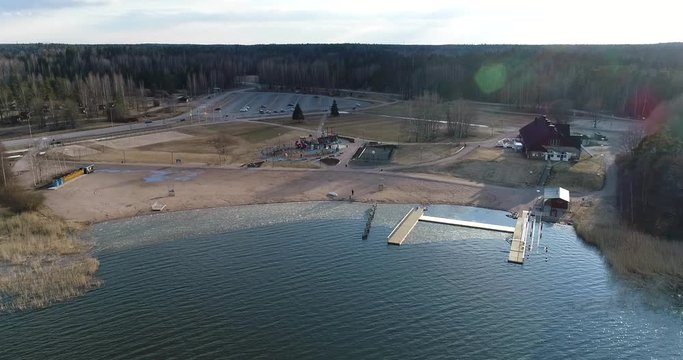 Oittaa, Cinema 4k aerial rising view tilting down towards Oittaa beach, at bodom lake, on a sunny spring day, in Espoo, Finland