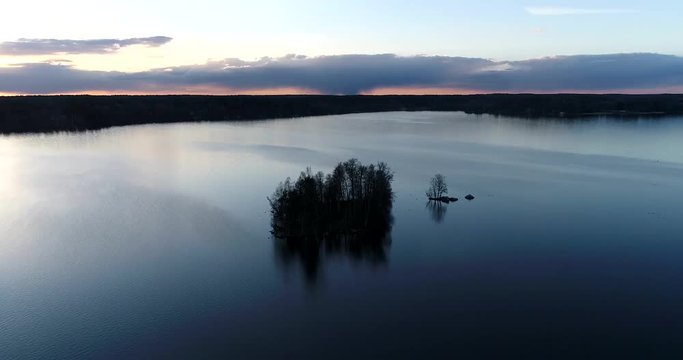 Lake bodom, Cinema 4k aerial flight around a little island on mirroring bodom lake, on a sunny spring evening, in Espoo, Finland