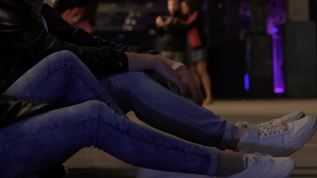 Legs of friends sitting on floor tired after party in club, night lifestyle