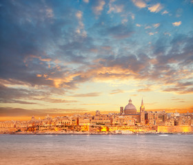 Beautiful spires and cathedral dome of Valletta under dramatic sky on the sunset