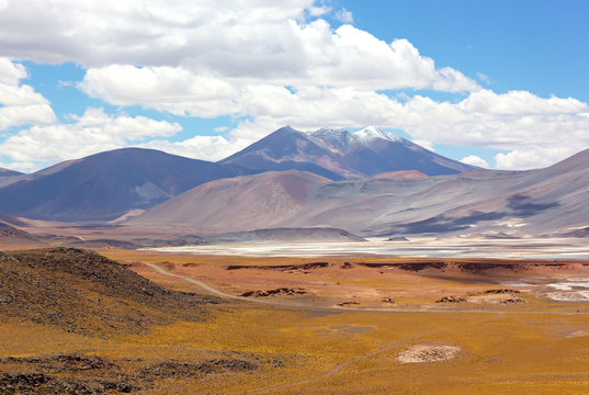 Volcanic mountains landscape of Atacama Desert, Chile. Colorful salt flats and mountains on horizon under white clouds.