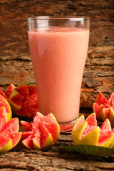 Organic pink guava smoothie in glass with sliced fruits.
