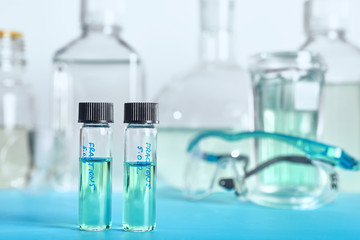 Two vials with liquid samples and histopathology tools as a background