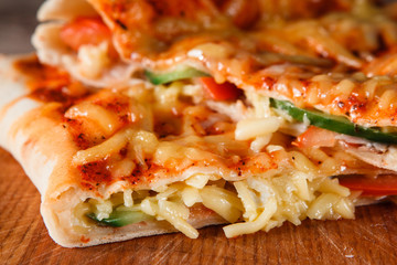 Closeup of fresh baked appetizing slices pizza calzone. Italian traditional food, restaurant menu photo.