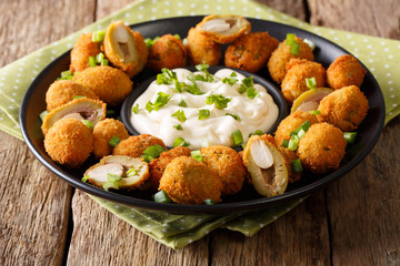 Tasty breaded fried olives with almonds close-up and creamy sauce. horizontal