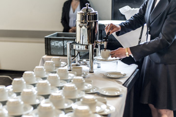 Abstract blurred many rows of coffee tea cups with coffee dispenser business people taking one