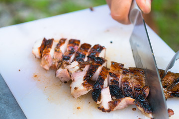 grilled meat cut on plastic cutting board, barbecue party