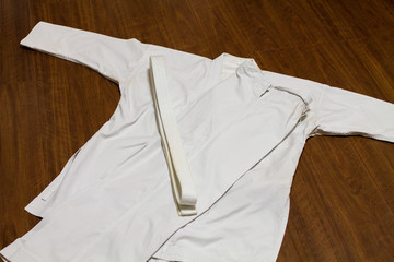 A white belt and Gi ( martial arts uniform ) on the wood floor