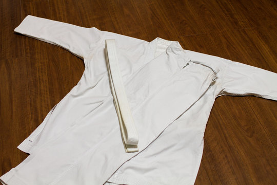 A white belt and Gi ( martial arts uniform ) on the wood floor